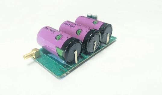 A group of three purple batteries sitting on top of a green board.